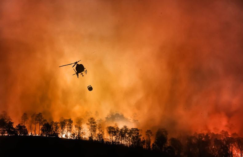 Aerial firefighting helicopter flying over a raging fire