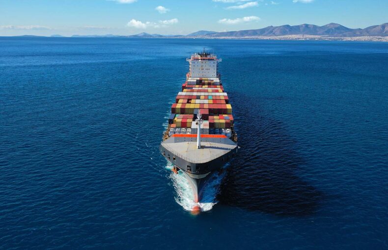 Maritime vessel carrying cargo containers cruising the Aegean deep blue sea