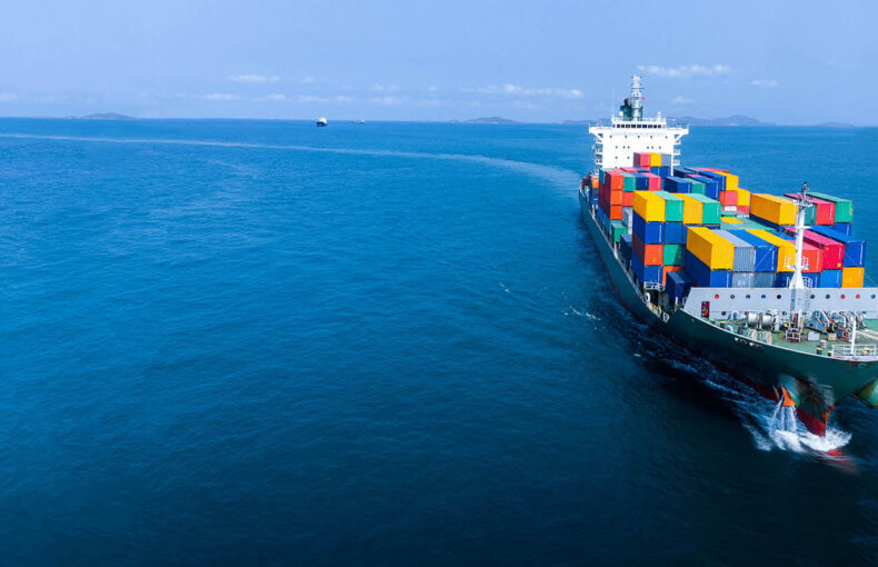 Aerial in front of cargo ship carrying containers
