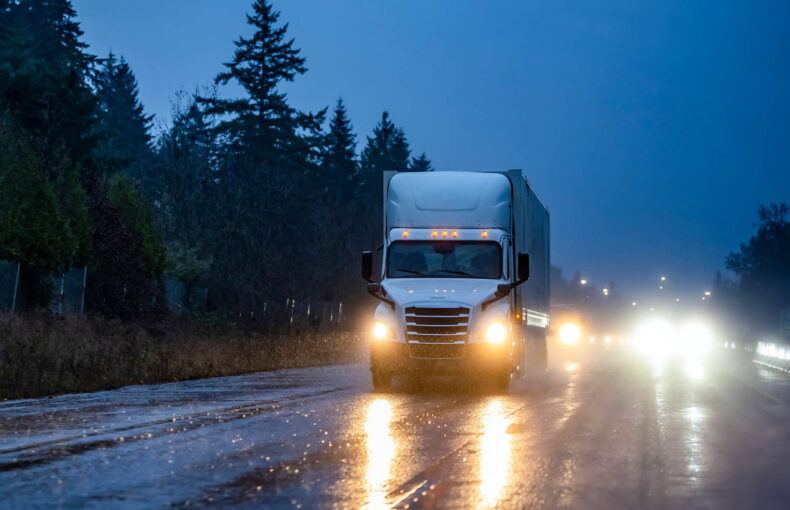 Semi truck transporting cargo at night in rainy weather