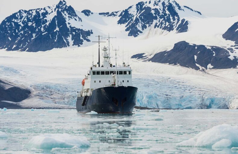 Exploration boat in front of glacier in icy water