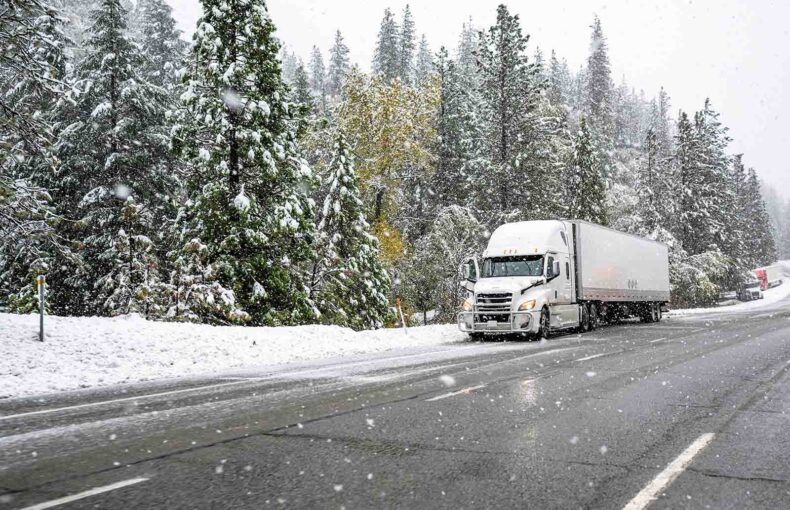 Semi-truck in the supply chain transporting goods on a winter highway during a snow storm