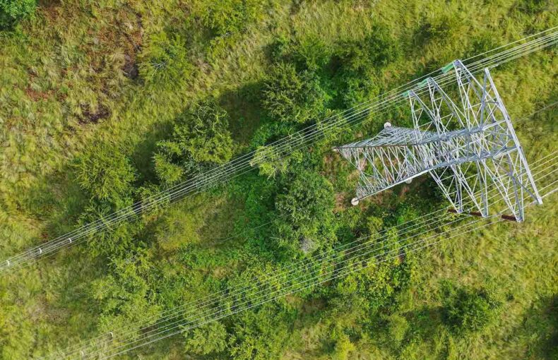 Aerial view of high voltage power pylons in field for utility and energy network
