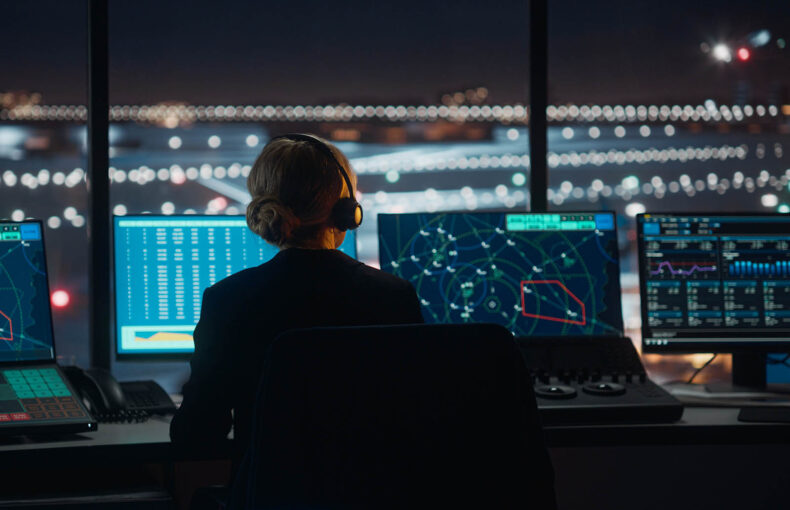 Air traffic controller with headset talks on a call in airport tower at night