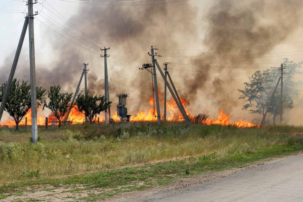 Electrical poles on fire in a field