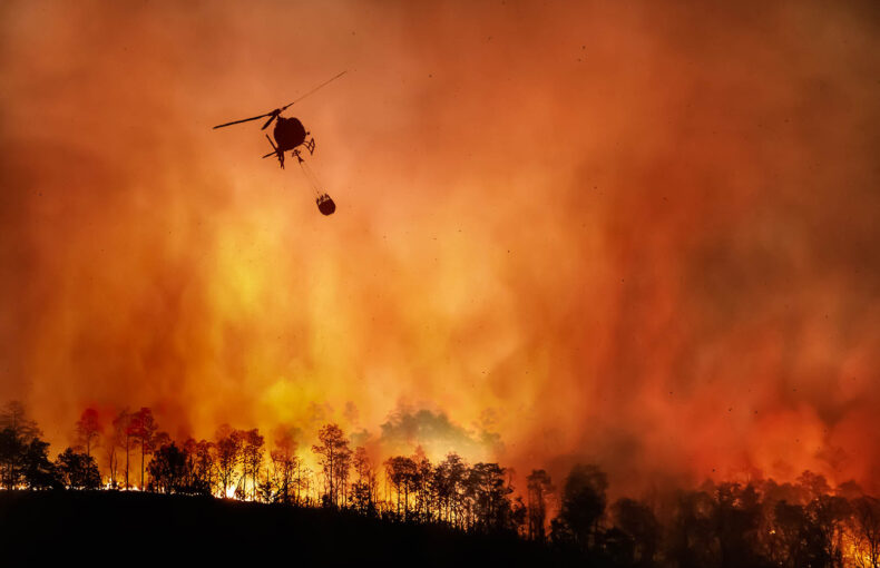 Fire fighting helicopter carry water bucket to extinguish forest fire