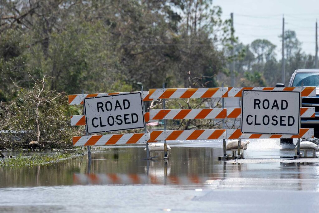 Flooded street in Florida after hurricane rainfall with road closed signs blocking access