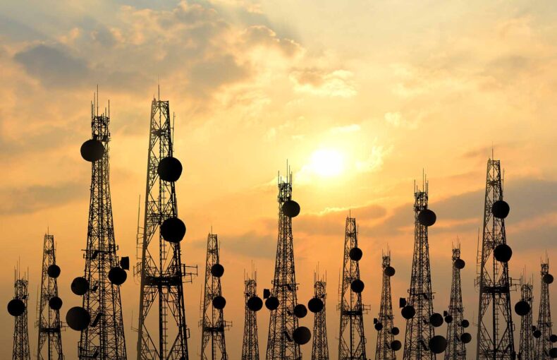 Satellite dish telecom network towers at sunset