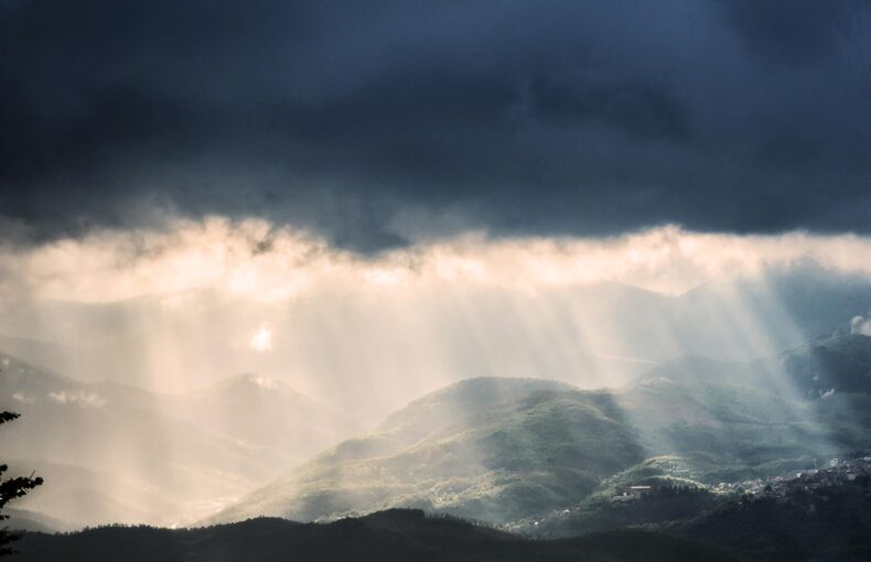 dark rain clouds with the sun's rays of lights bursting through