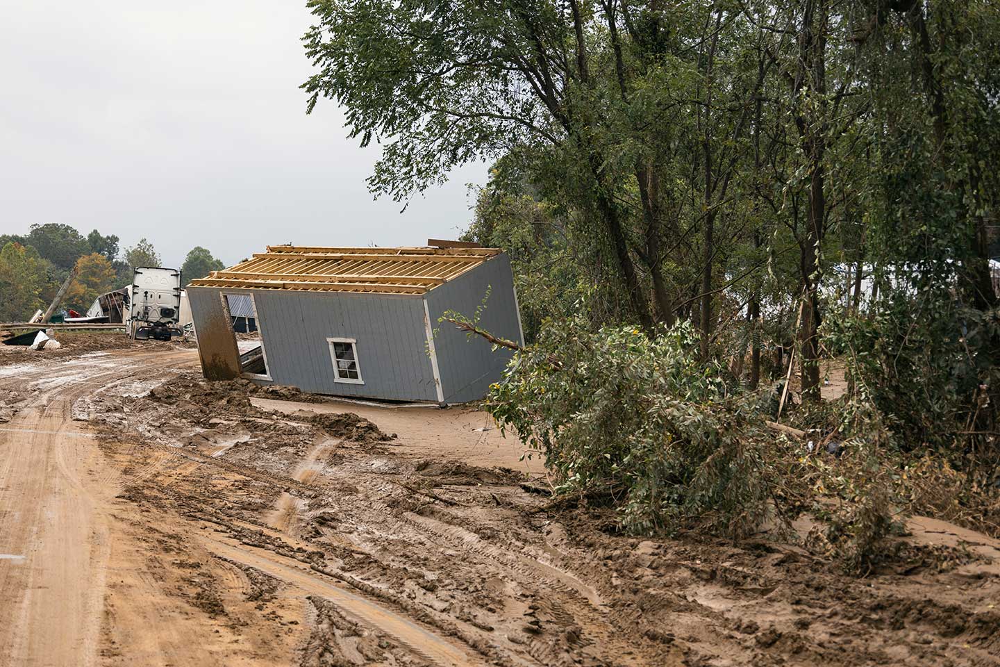 The impact of hurricane Helene. A building flipped over and trucks stuck in mud in the background. Spire's data can be used to help businesses plan for these events and move assets out of harm's way.