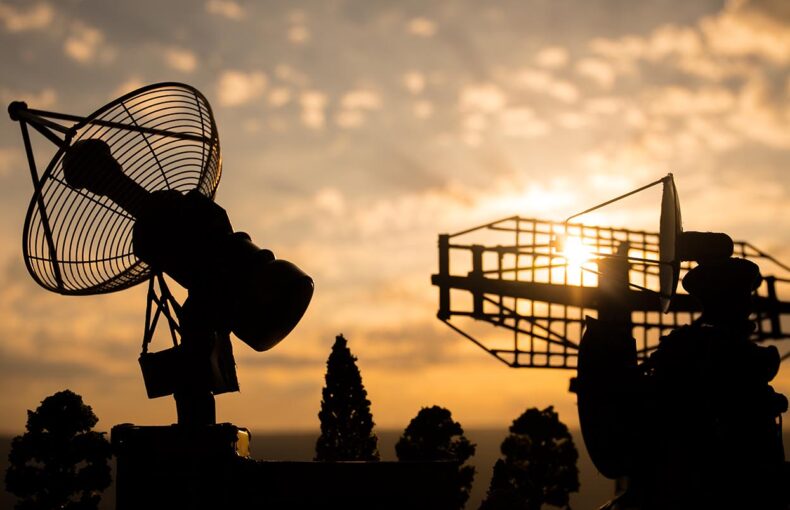 Silhouettes of satellite dishes or radio antennas against sunset sky